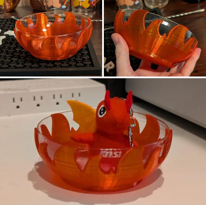 A brilliant 3D printed orange flame-patterned bowl, with a small dragon toy inside, highlighting clever 3D printers.