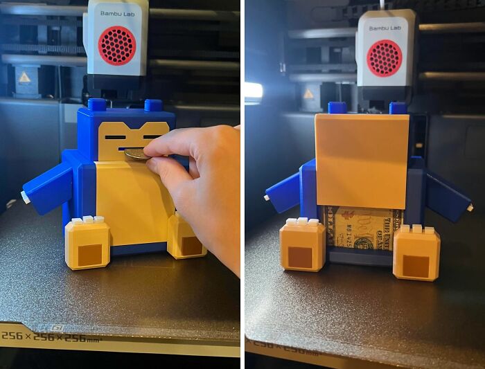 A blue and yellow Snorlax piggy bank made with 3D printers, with a hand inserting a coin.