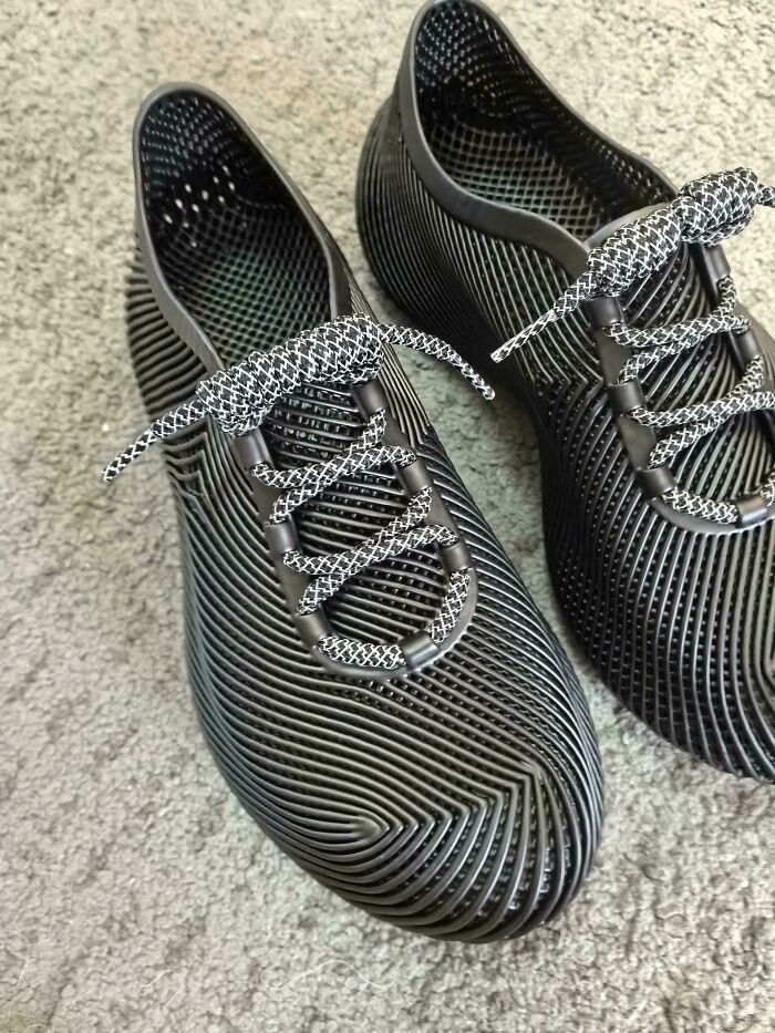 A pair of black, textured shoes with white and black laces, showcasing innovative design made with 3D printers.