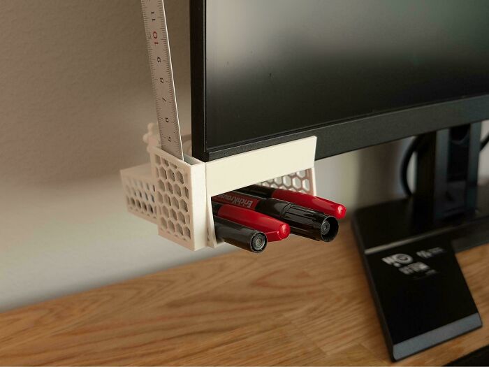 A clever 3D printed monitor attachment holding pens and a ruler, optimizing desk space.