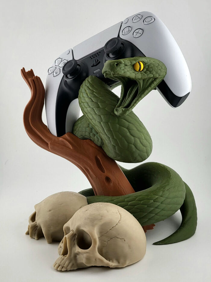 A 3D printed snake controller holder for a PS5 controller, with skulls at the base.
