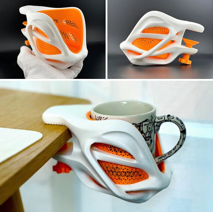 A white and orange cup holder, a brilliant thing demonstrating the practical uses of 3D printers, clamped to a desk.