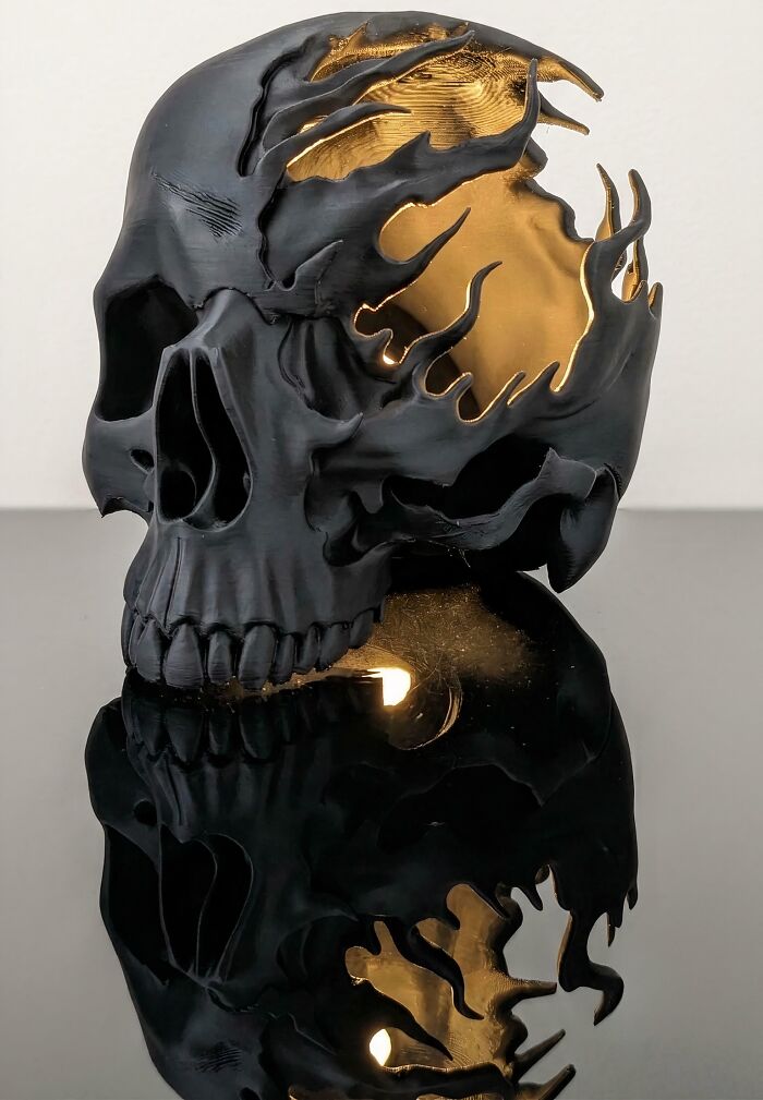 A dark, skull-shaped lamp with golden interior accents, demonstrating the brilliant things possible with 3D printers.