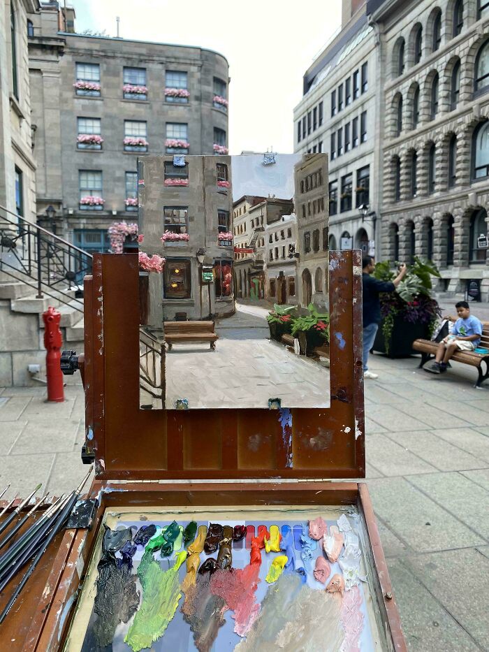 An easel with an oil painting of a city street, a weird and wonderful art scene.