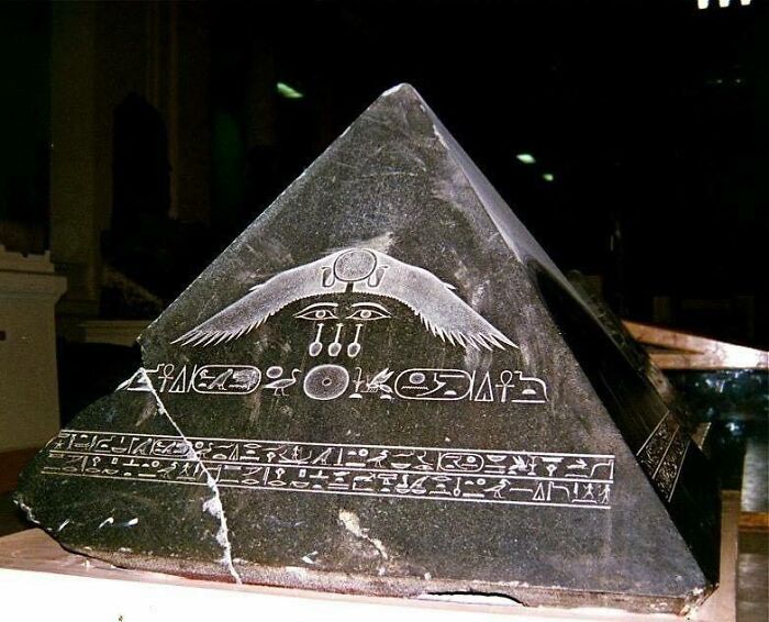 A black pyramid-shaped object with ancient Egyptian hieroglyphs, a weird and wonderful artifact.