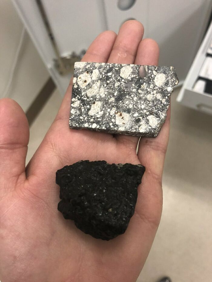 A hand holds two rock samples, one speckled grey and white, the other black and porous, showcasing wonderful geology.