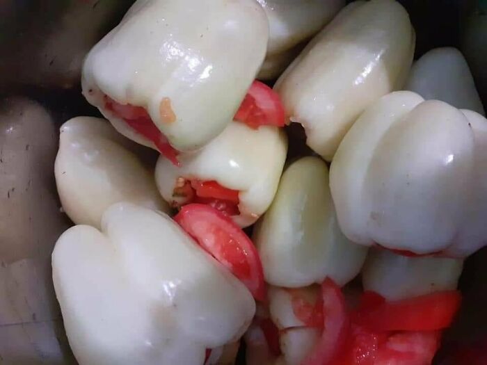 A close-up of white bell peppers stuffed with red tomatoes, a wonderful and weird culinary preparation.