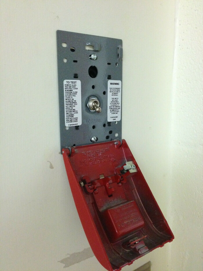 A partially disassembled fire alarm pull station, revealing its internal components, part of the weird and wonderful world.