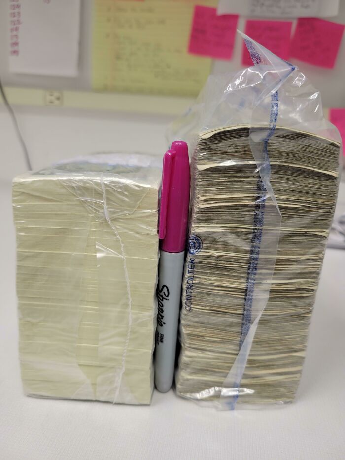 Two large stacks of cash, wrapped in plastic, with a pink Sharpie marker for scale, highlighting a wonderful world discovery.