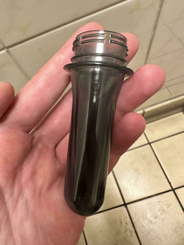 A hand holding a clear plastic preform, appreciating the weird and wonderful world.