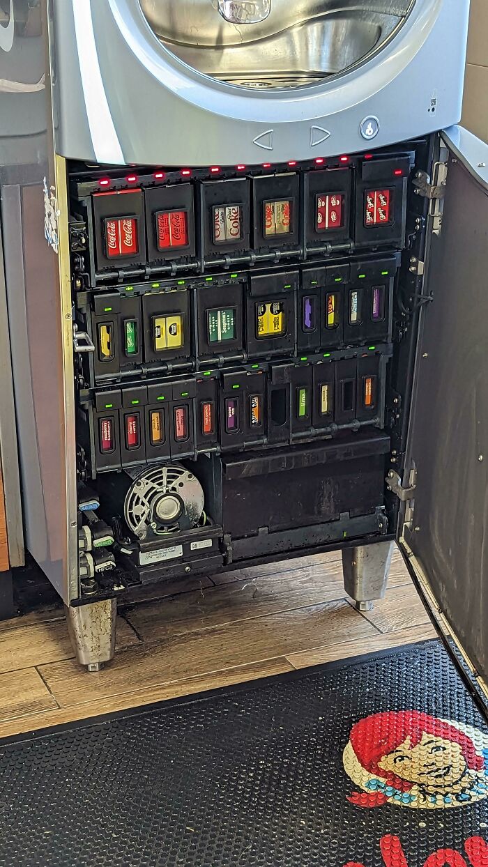 An open soda fountain machine revealing rows of flavor cartridges, a wonderful and weird sight of beverage technology.
