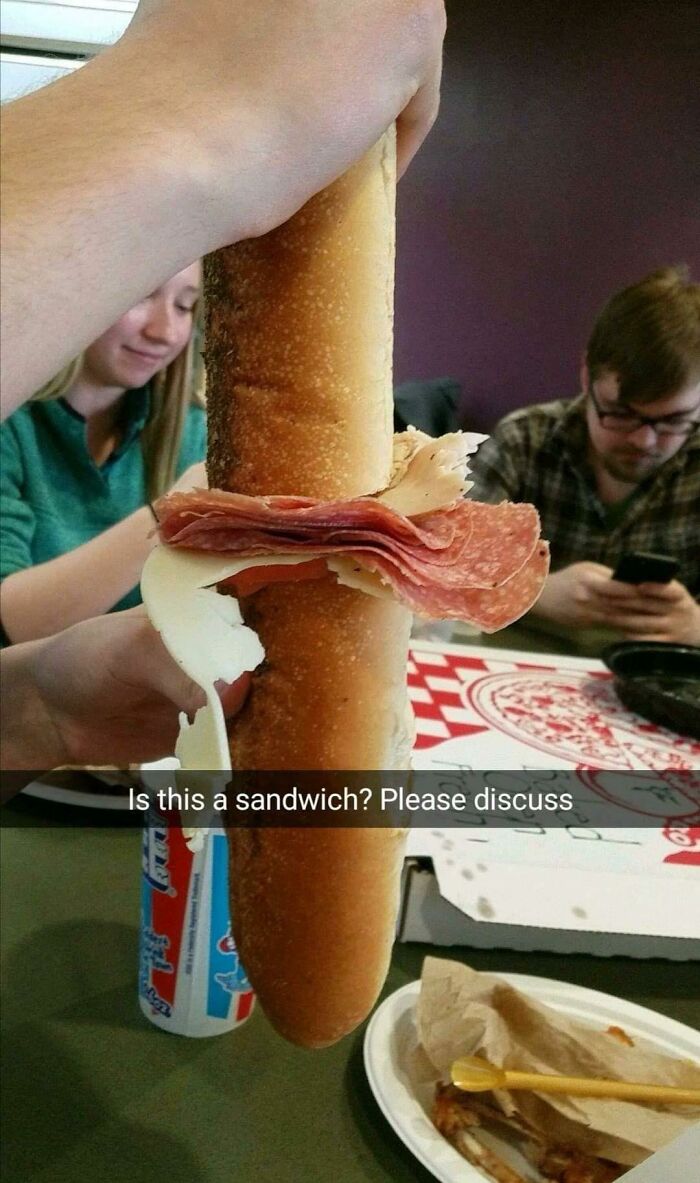 A person holding an unusually long sandwich, making for a weird and wonderful picture of food.