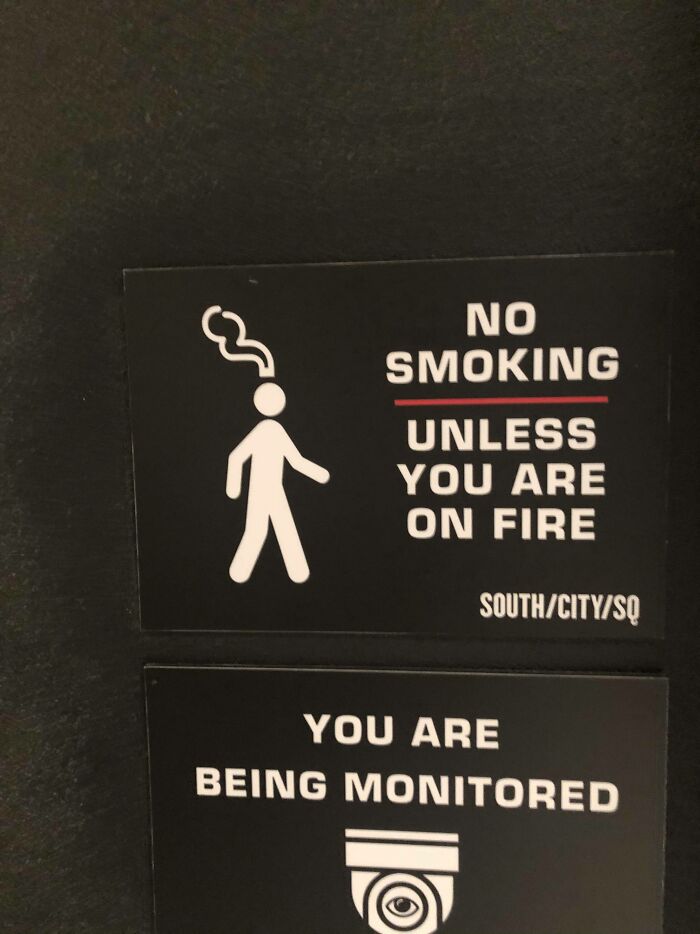 A humorous no smoking sign, unless you are on fire, adding a weird and wonderful touch to a public space.