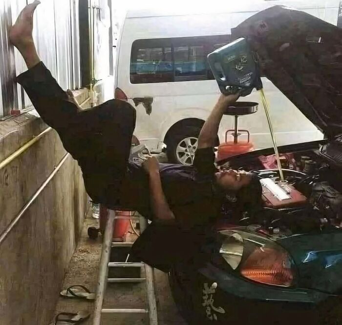 A funny meme of a person lying upside down to pour oil into a car engine, demonstrating car maintenance improvisation.