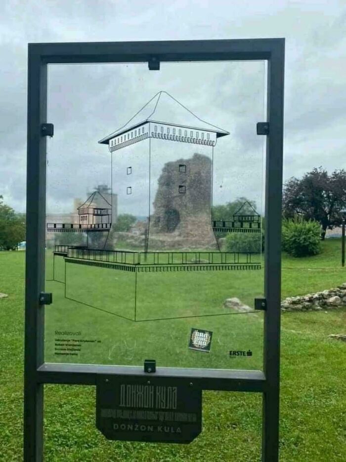 A transparent sign showing an architectural drawing of a medieval tower superimposed over its actual ruins, highlighting the wonderful preservation.