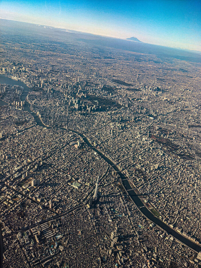 An aerial shot of a sprawling urban landscape with a river winding through it, and a distant mountain, a wonderful view of the world.