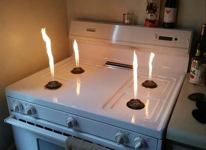 A wild picture of a white kitchen stove with four lit burners, displaying the weird and wonderful world.