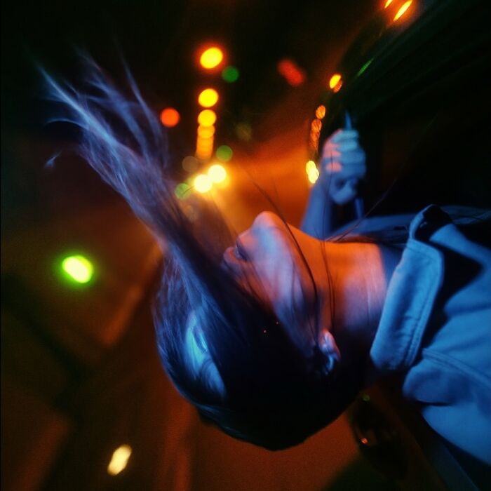 A woman with hair flowing, illuminated by blue and orange neon lights, creating a cinematic portrait.