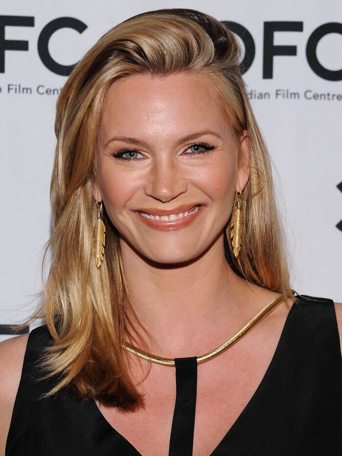 Natasha Henstridge smiling at an event, showcasing her blonde hair and gold jewelry, highlighting her impressive career.