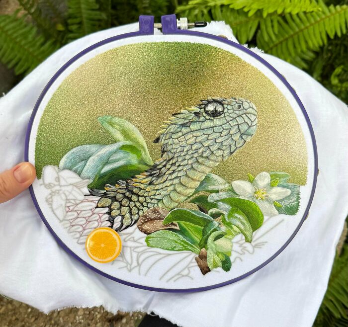 Detailed embroidery projects featuring a green spiny bush viper among leaves and white flowers in a hoop