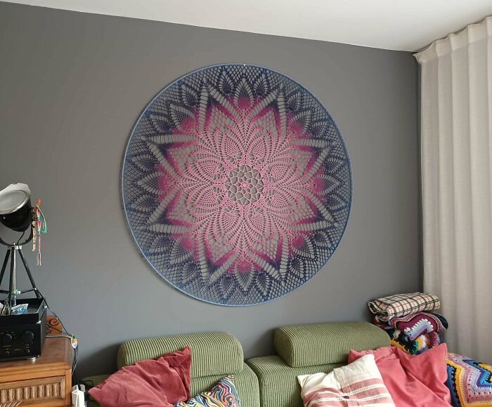 Large crochet wall hanging with pink and blue floral design in living room