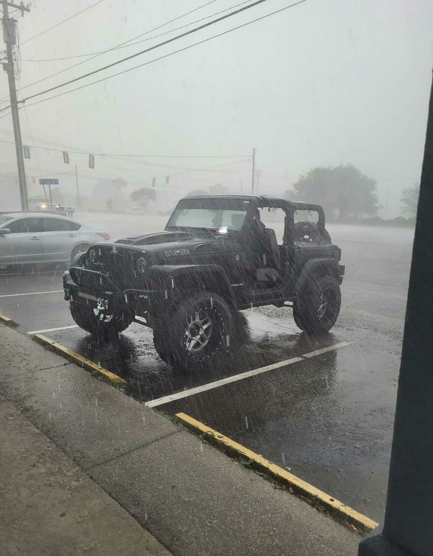 Funny fails: A Jeep Wrangler parked on a street during a heavy rainstorm with its soft top removed.