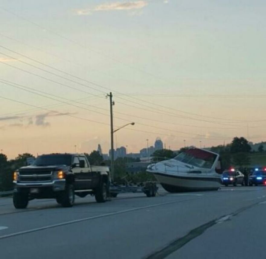 Funny fails: A boat detached from its trailer and overturned on a highway, with police cars nearby.