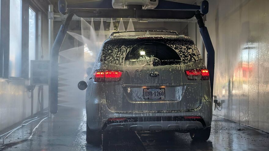 A silver SUV covered in soap suds inside an automatic car wash, a funny regret.