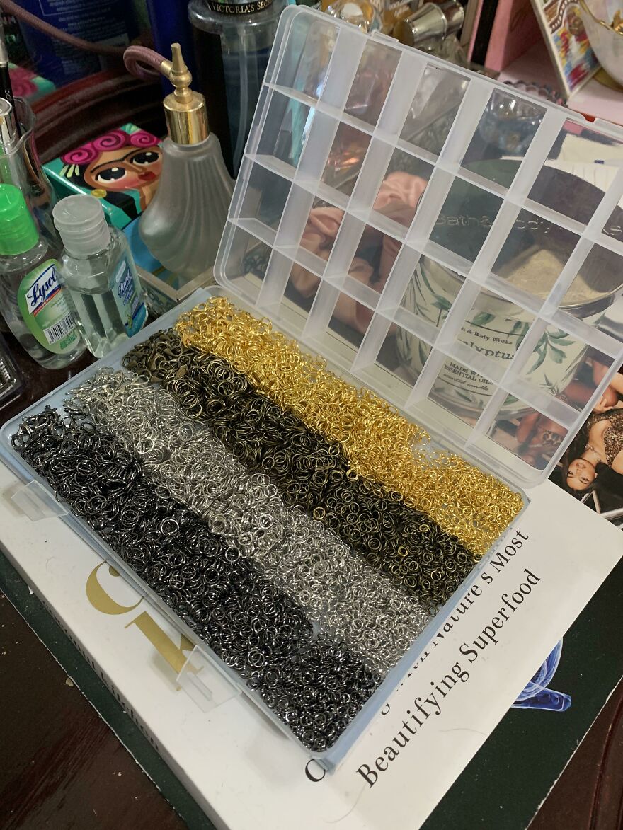 An open clear plastic organizer box filled with small metal rings in various colors, not a fails.
