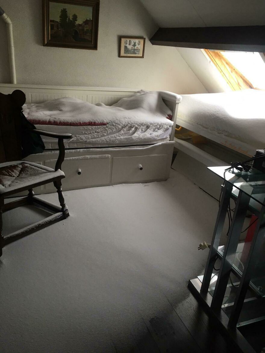 A bedroom with a bed and floor covered in snow from an open window, a funny unfortunate regret.