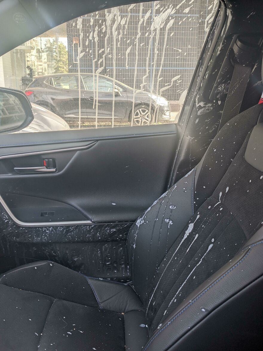 An interior car shot shows funny unfortunate regrets fails with white liquid splattered on the window, door, and passenger seat.