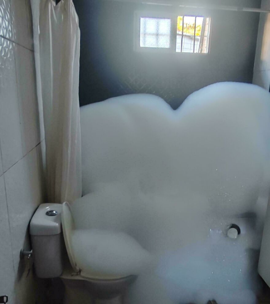 A bathroom overflowing with bubbles from the toilet and bathtub, a funny unfortunate cleaning fail.