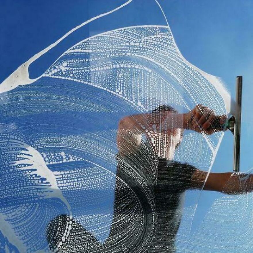 A person cleaning a window, making extra dough through their side hustle.