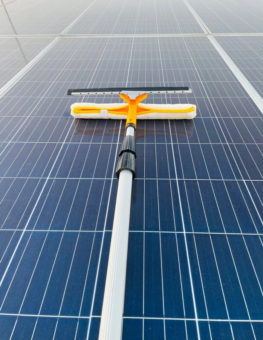 A squeegee cleaning a solar panel, showcasing a practical side hustle.