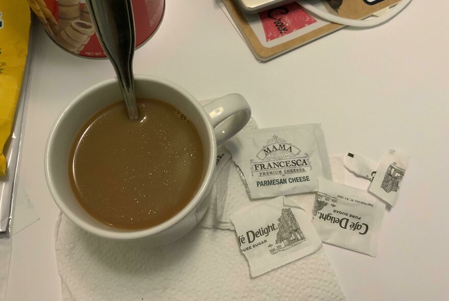 A coffee mug with a parmesan cheese packet mistakenly used as a sugar substitute, an unfortunate fail.