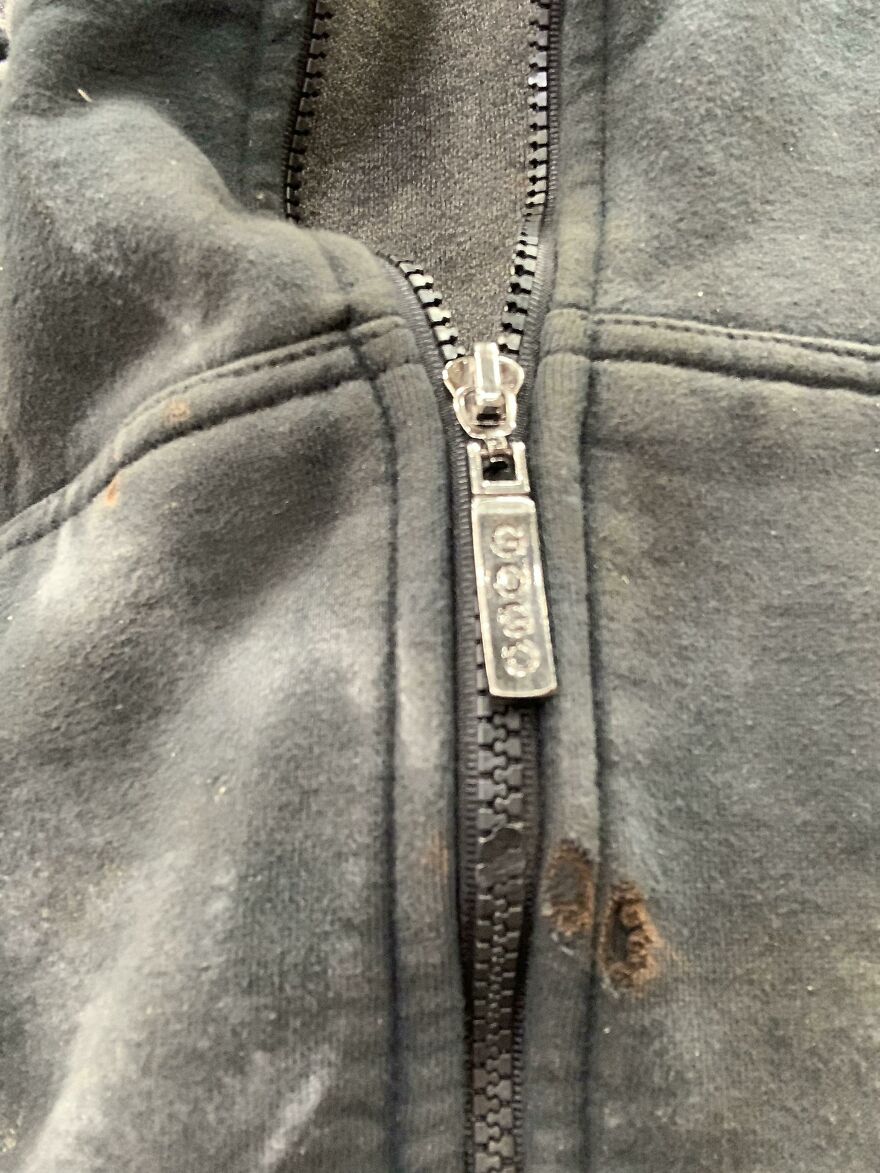 A black zipped hoodie with a burnt hole near the zipper, an unfortunate regret.