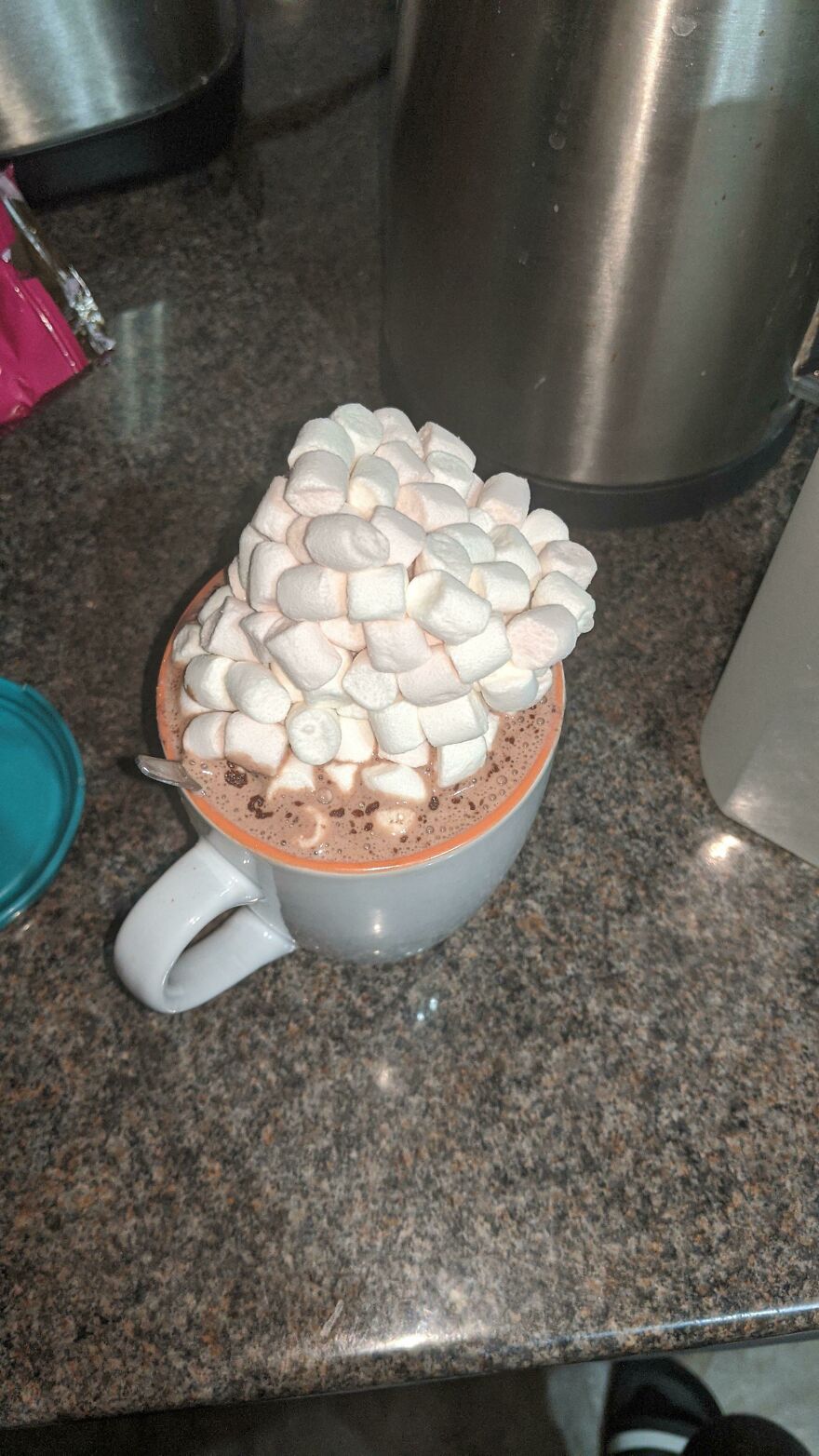 Funny unfortunate regret: a white mug overflowing with hot chocolate and an excessive amount of mini marshmallows, a sweet fail.