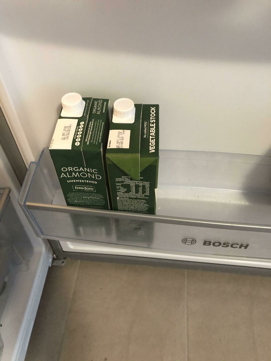 Funny unfortunate regret: a fridge shelf with two similar green cartons, one organic almond milk and one vegetable stock, a shopping fail.