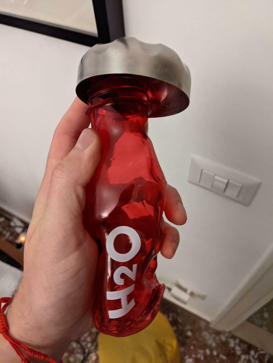 Funny unfortunate regret: a hand holding a red H2O bottle with a severely dented bottom, a clear product fail.
