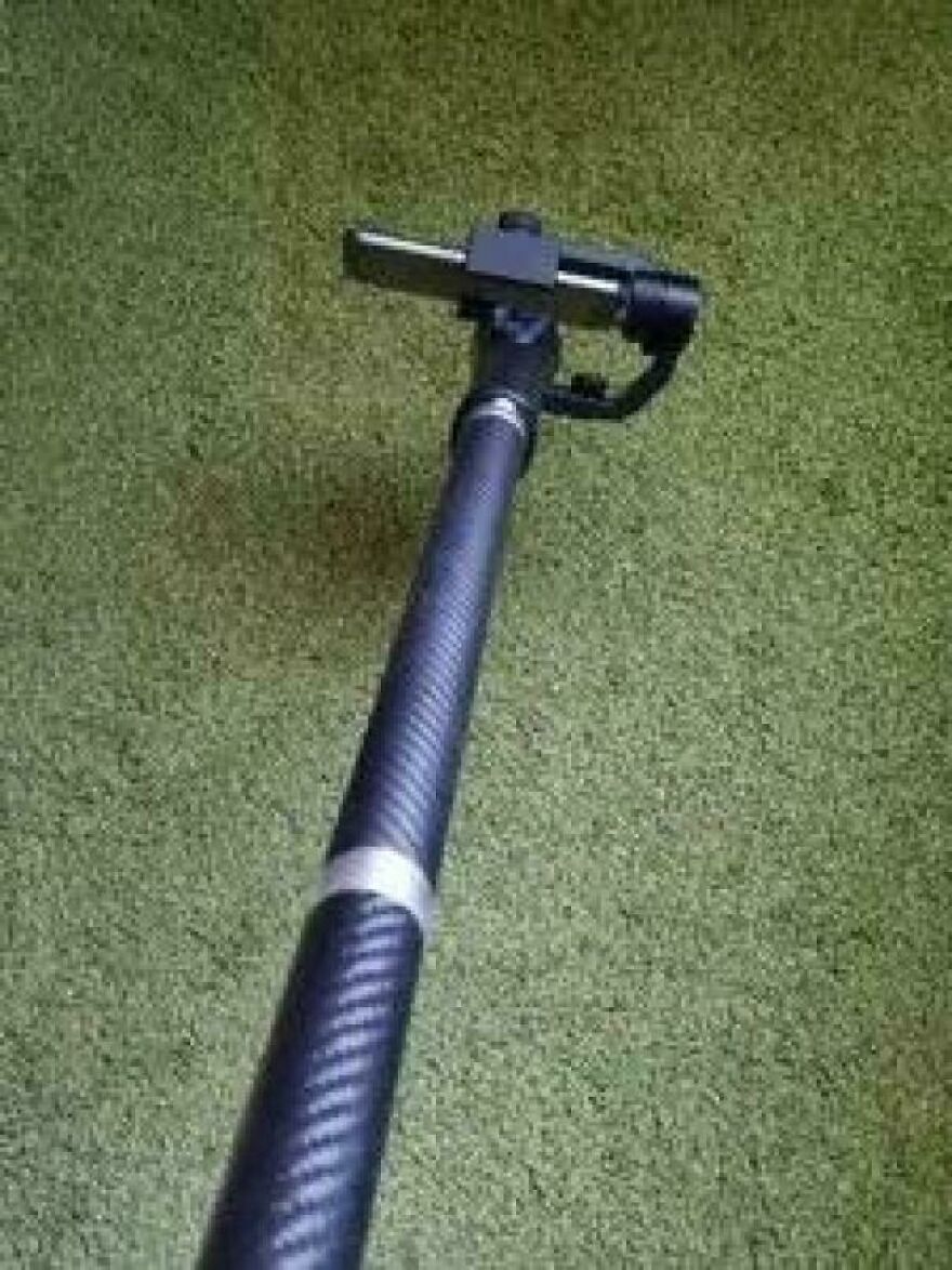 A black camera monopod with a textured grip against a green background, useful for photography side hustles.