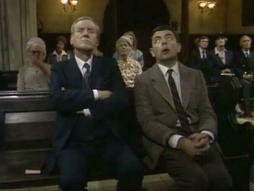 Mr. Bean and another man in a church pew, looking bored during a service, showcasing a weird side hustle scenario.