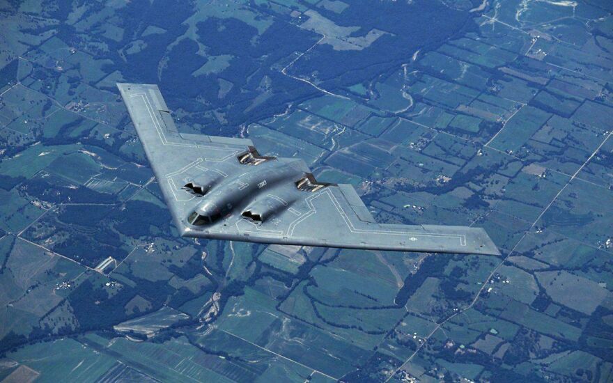 A B-2 Spirit stealth bomber flying over a landscape, an incredible thing happening on Earth.