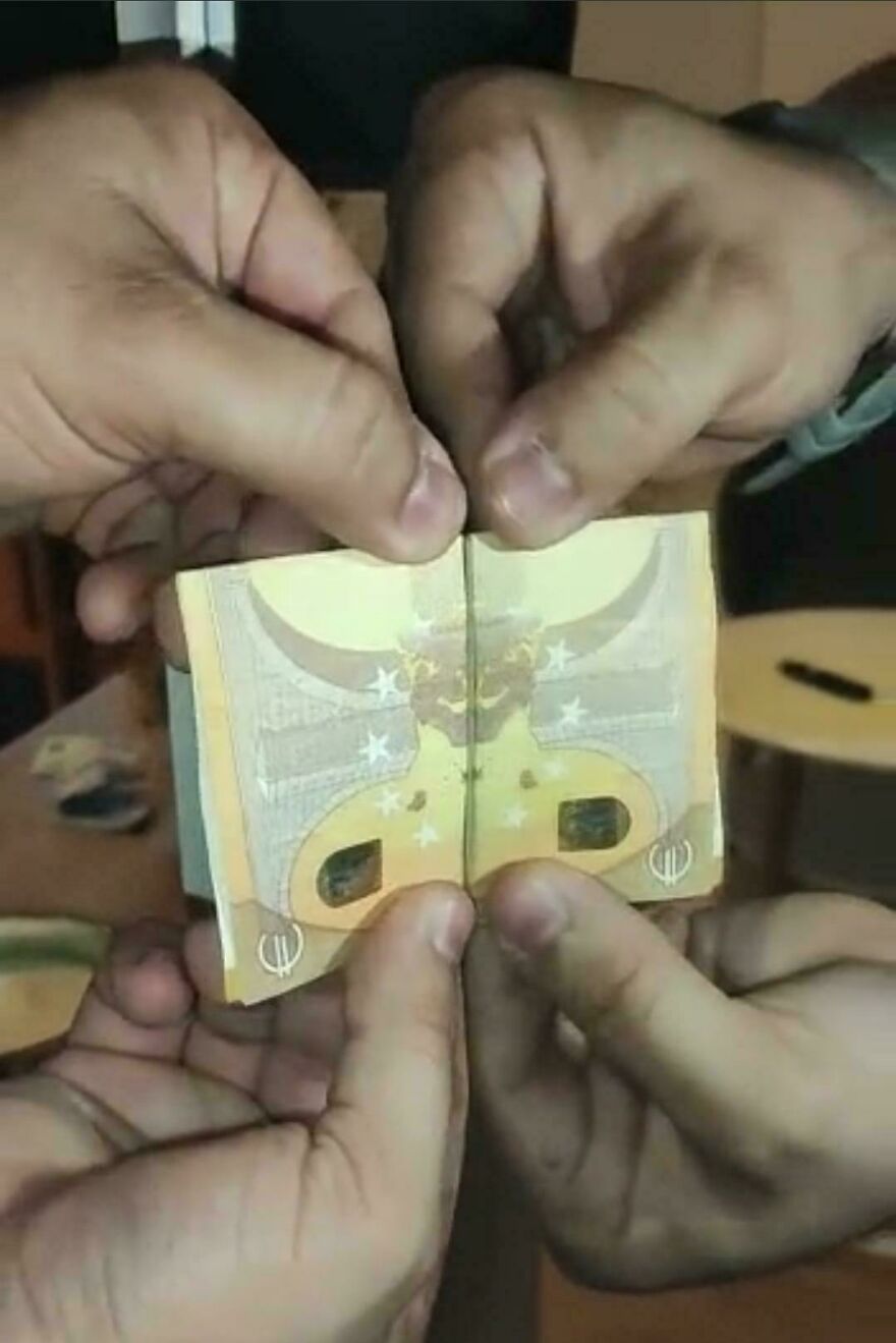 Hands holding a 50 euro banknote folded in half to reveal a strange face, an incredible thing happening on Earth.