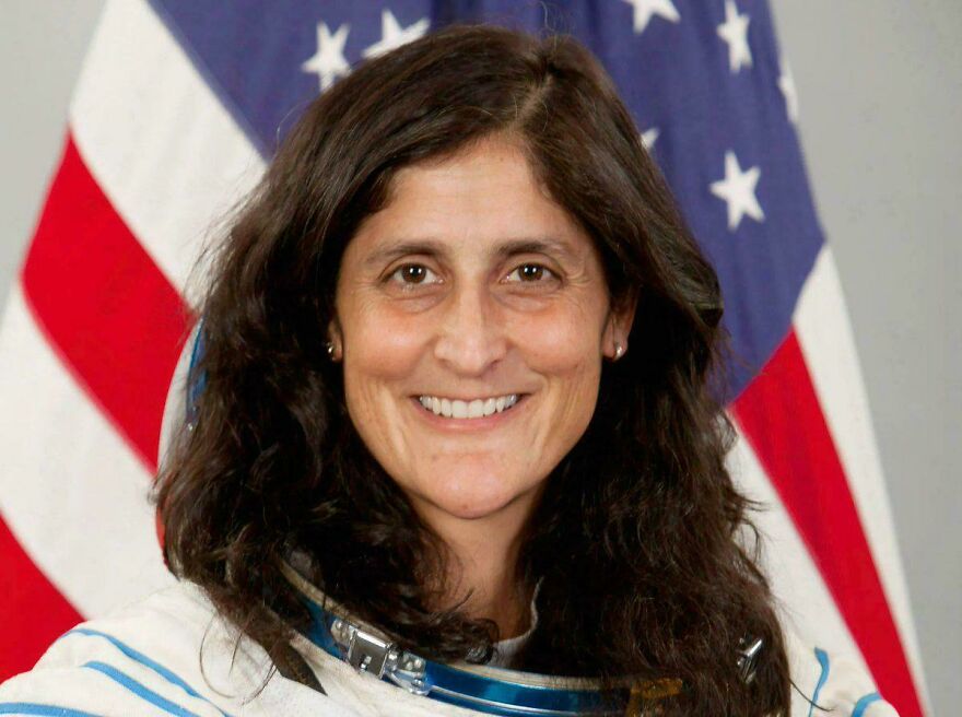 Smiling astronaut in front of an American flag. Strange things happening on Earth that look almost too incredible.
