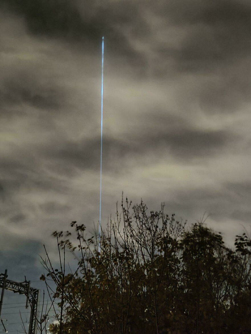 Strange thing happening on Earth: A bright, vertical beam of light piercing through a cloudy night sky.
