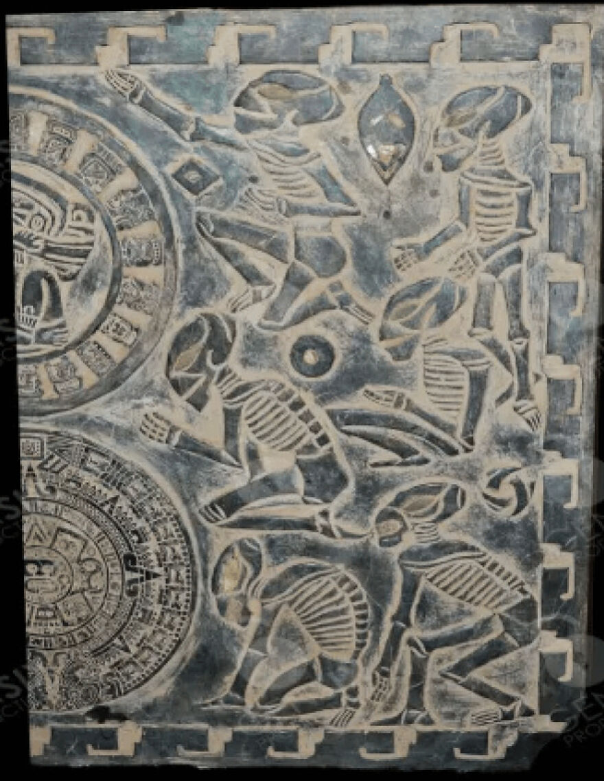 Strange things happening on Earth: an ancient stone tablet with detailed carvings of skeletal figures and circular patterns.