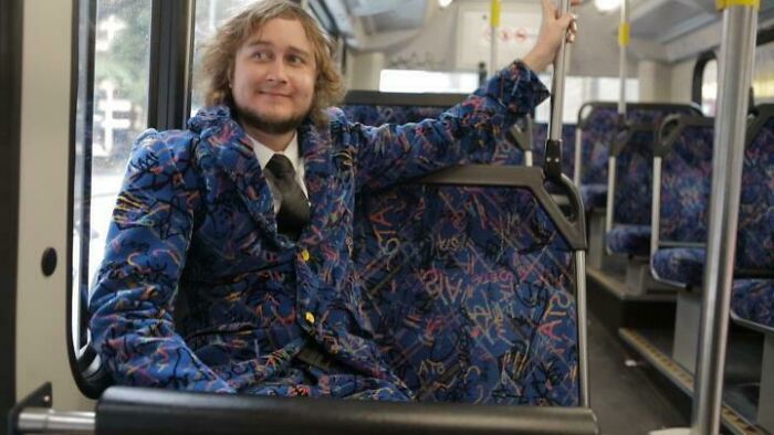 Man in a matching blue graffiti patterned suit on a public bus, a bad fashion crime example