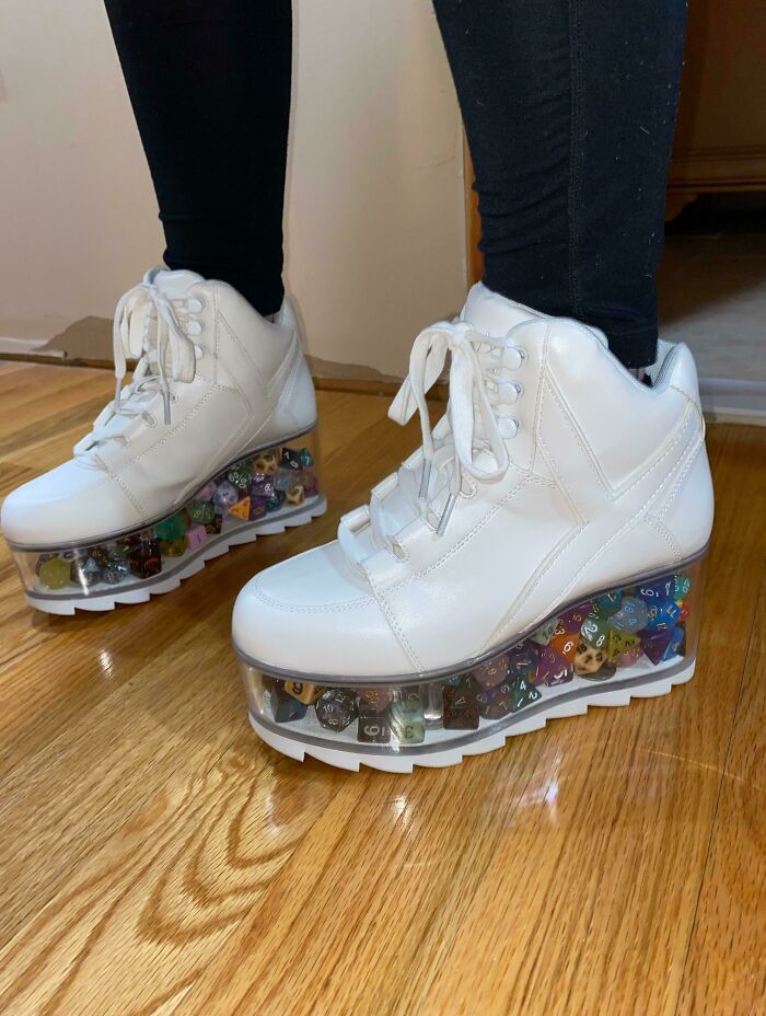 A pair of white platform sneakers with transparent soles filled with colorful dice, a truly bad fashion crime.