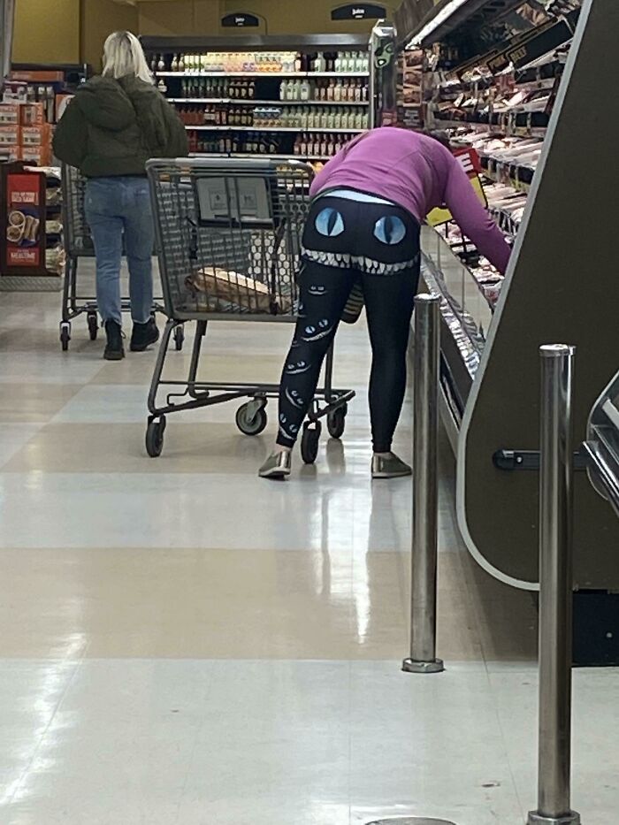 A shopper in a grocery store wearing hilariously bad fashion crime leggings with a monster face.