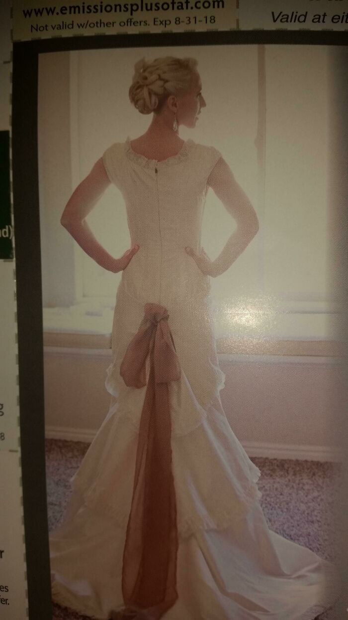 A woman models a bad fashion crime wedding dress with a long brown bow at the back.